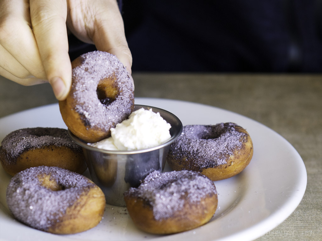person dunking doughnuts into cream at one of the best restaurants in Skagit County, WA